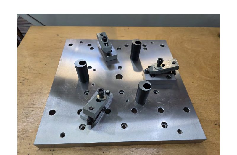 Clamping fixture for the cast stator housings: base plate with spacer bushings and clamping claws.